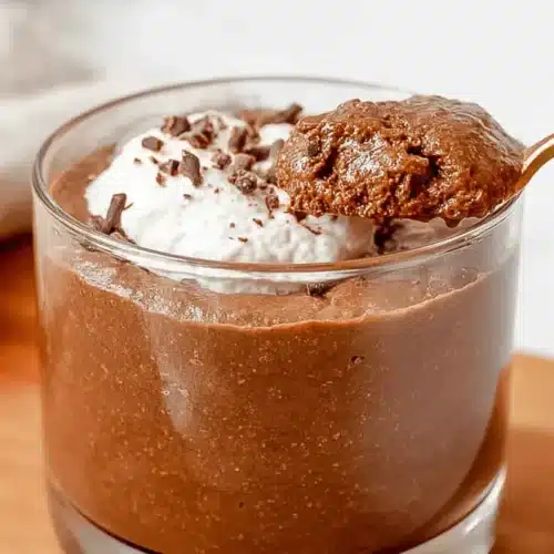 The Best High-Protein Chocolate Mousse: Easy 4-Ingredient Recipe 3 Close-up of a spoonful of rich High-Protein Chocolate Mousse being lifted from a glass, topped with whipped cream and chocolate shavings.