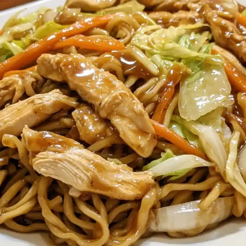 Close-up of chicken yakisoba noodles with tender chicken, cabbage, carrots, and glossy savory stir-fry sauce.