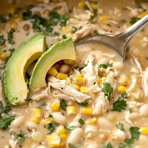 Easy White Chicken Chili Crockpot Recipe 2 A spoonful of White Chicken Chili Crockpot, garnished with avocado, sour cream, and crispy tortilla strips.