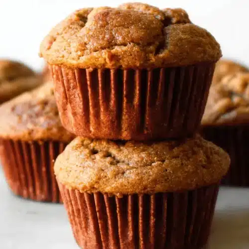 Deliciously golden-brown Banana Bread Muffins, freshly baked and stacked, with a beautifully craggy top.
