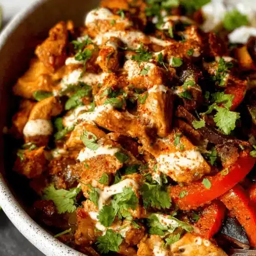 The Best Chicken Fajita Bowl recipe 2 Vibrant Chicken Fajita Bowl with seasoned chicken, colorful bell peppers, rice, cilantro, and a creamy sauce.