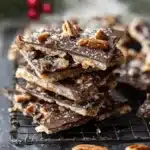 Homemade chocolate and nut bark, a delicious christmas crack recipe, stacked on a cooling rack in a festive holiday setting.