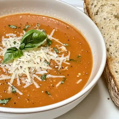 Perfect Fresh Tomato Soup Recipe, creamy red tomato soup with basil and cheese garnish in a white bowl.