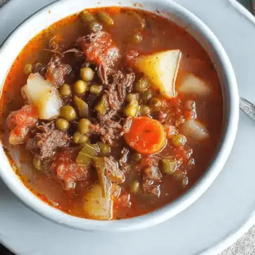 Hearty bowl of rustic vegetable beef soup recipe with potatoes, carrots, and peas.