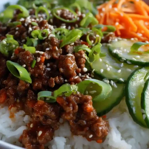 Ground Beef Bowl: Quick, Healthy & Flavorful! 2 Ground beef bowl with rice, cucumbers, shredded carrots, and sesame seeds.