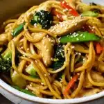 A vibrant bowl of Gluten Free Chicken Lo Mein, brimming with tender chicken, colorful vegetables, and a savory sauce, garnished with sesame seeds.