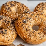 Close-up of four freshly baked, golden-brown everything bagels, highlighting the simplicity of Two-Ingredient Protein Bagels.
