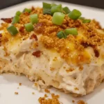 Million dollar chicken casserole topped with melted cheese, crispy golden crumbs, and green onions on a white plate.