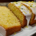 The Best Lemon Pound Cake Recipe with Icing sliced and topped with sweet lemon glaze on a white plate.