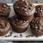 Close-up of rich High Protein Greek Yogurt Chocolate Muffins with chocolate chips on a white tray.