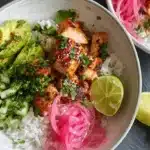 Overhead view of vibrant Honey Lime Chicken & Rice Bowls with avocado, pickled onions, and fresh cilantro.