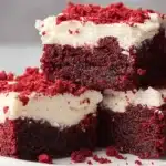 Decadent Red Velvet Brownies with creamy white frosting and cake crumbs.