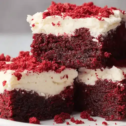 Decadent Red Velvet Brownies with creamy white frosting and cake crumbs.