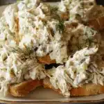 Appetizing creamy chicken salad with fresh dill garnish on toasted baguette, perfect for a dill pickle chicken salad recipe.