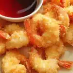 Crispy golden shrimp tempura served with a vibrant red dipping sauce.
