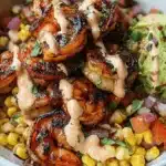 A vibrant Grilled Shrimp Bowl Recipe featuring plump, charred shrimp, fresh guacamole, corn, pico de gallo, and a creamy sauce in a white ceramic bowl.