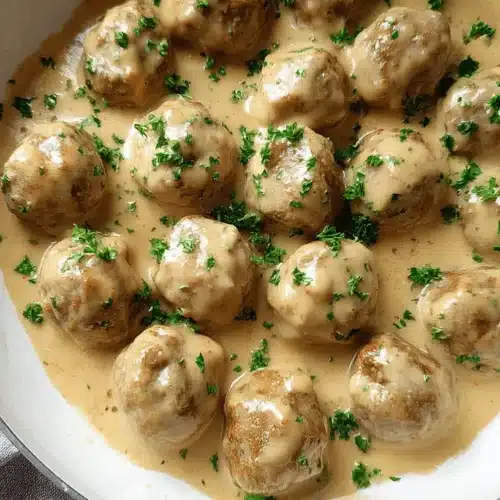 An overhead view of a pan brimming with creamy Swedish meatballs, garnished with fresh parsley, perfect for a classic Swedish meatballs recipe.
