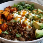 Ground beef cottage cheese bowl with avocado, roasted sweet potatoes, and rice topped with sauce and fresh herbs.