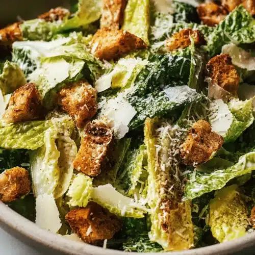 Vibrant Caesar salad with crisp romaine, golden croutons, and Parmesan in a rustic bowl.