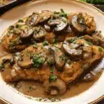 Two generous portions of chicken marsala with mushrooms and fresh parsley on an elegant plate.