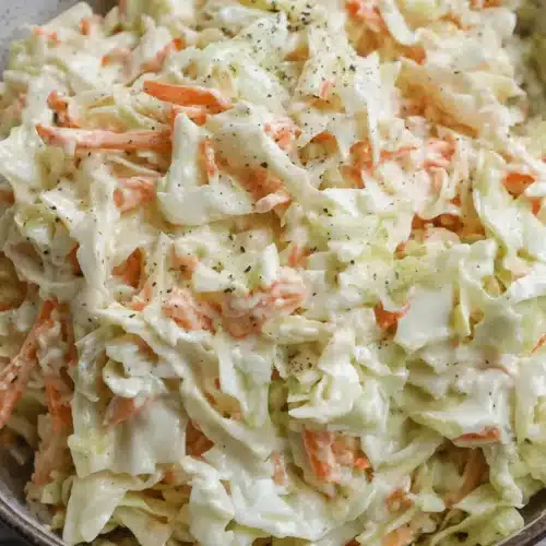 Close-up of a bowl of freshly prepared, creamy coleslaw with shredded cabbage and carrots, highlighting a delicious coleslaw recipe.