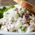 Appetizing creamy tuna salad recipe served with crisp toast and fresh lettuce on a white plate.