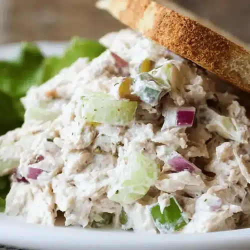 Classic Tuna Salad Recipe 2 Appetizing creamy tuna salad recipe served with crisp toast and fresh lettuce on a white plate.